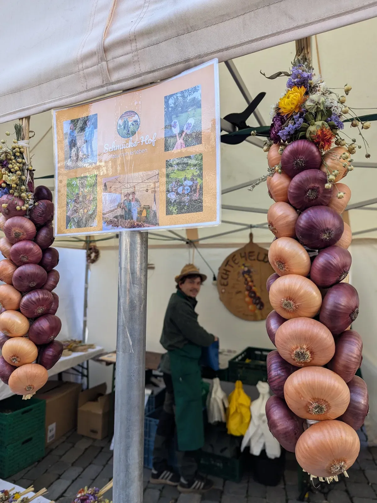 Marktstand mit Zwiebelzöpfen und Trockenblumen unter einem Pavillon