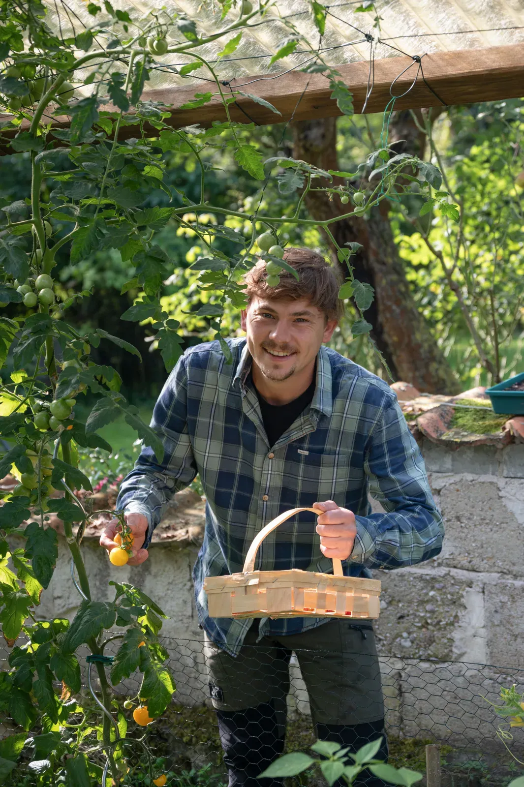 Jonas steht mit einem Korb im Garten des Schmücke-Hofs